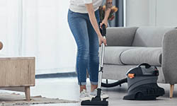Limpeza em pisos e paredes: mulher passando aspiraor de pó, usando jeans
